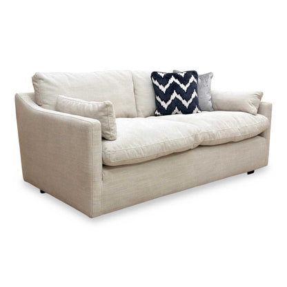 Full view of Nick Scali Dream 2 seater sofa upholstered in soft natural fabric with a streamlined silhouette.