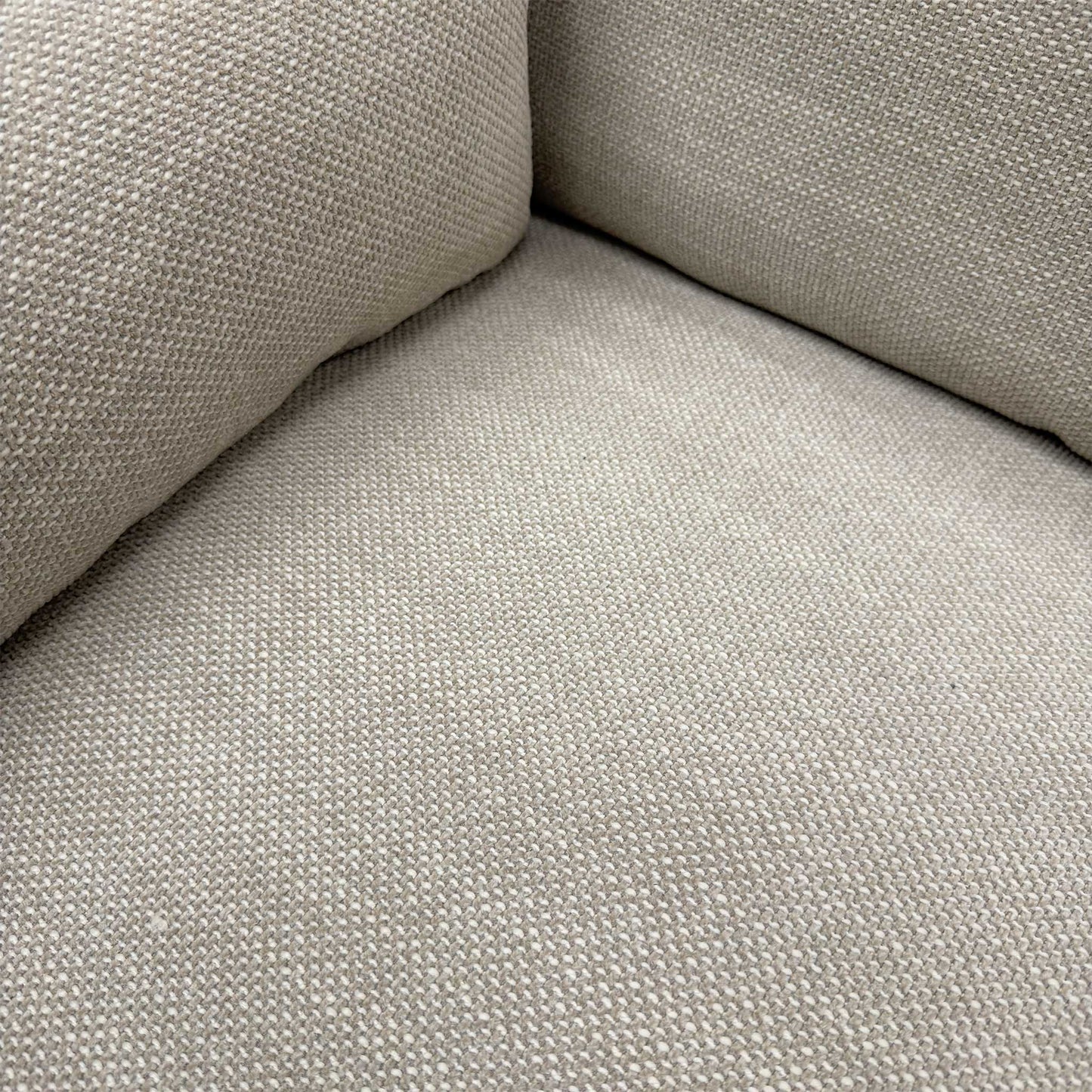 Close-up of the natural fabric upholstery and the high-quality stitching on the sofa armrest.