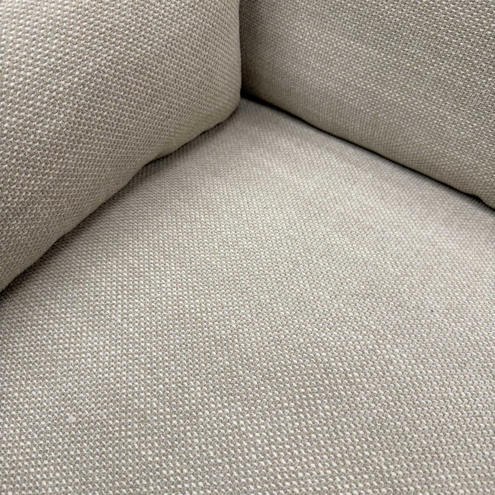 Close-up of the natural fabric upholstery and the high-quality stitching on the sofa armrest.