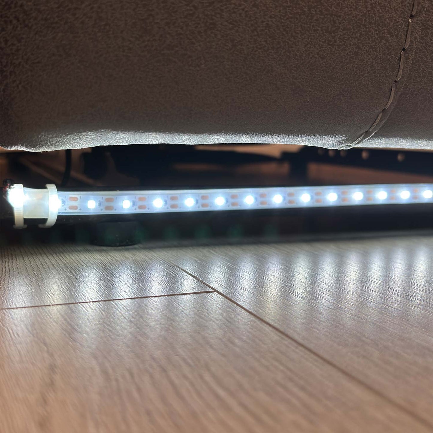 Close-up view of the 'Vegas' charcoal grey power recliner chair featuring integrated blue LED ambient lighting along the base for a modern, cinematic look.