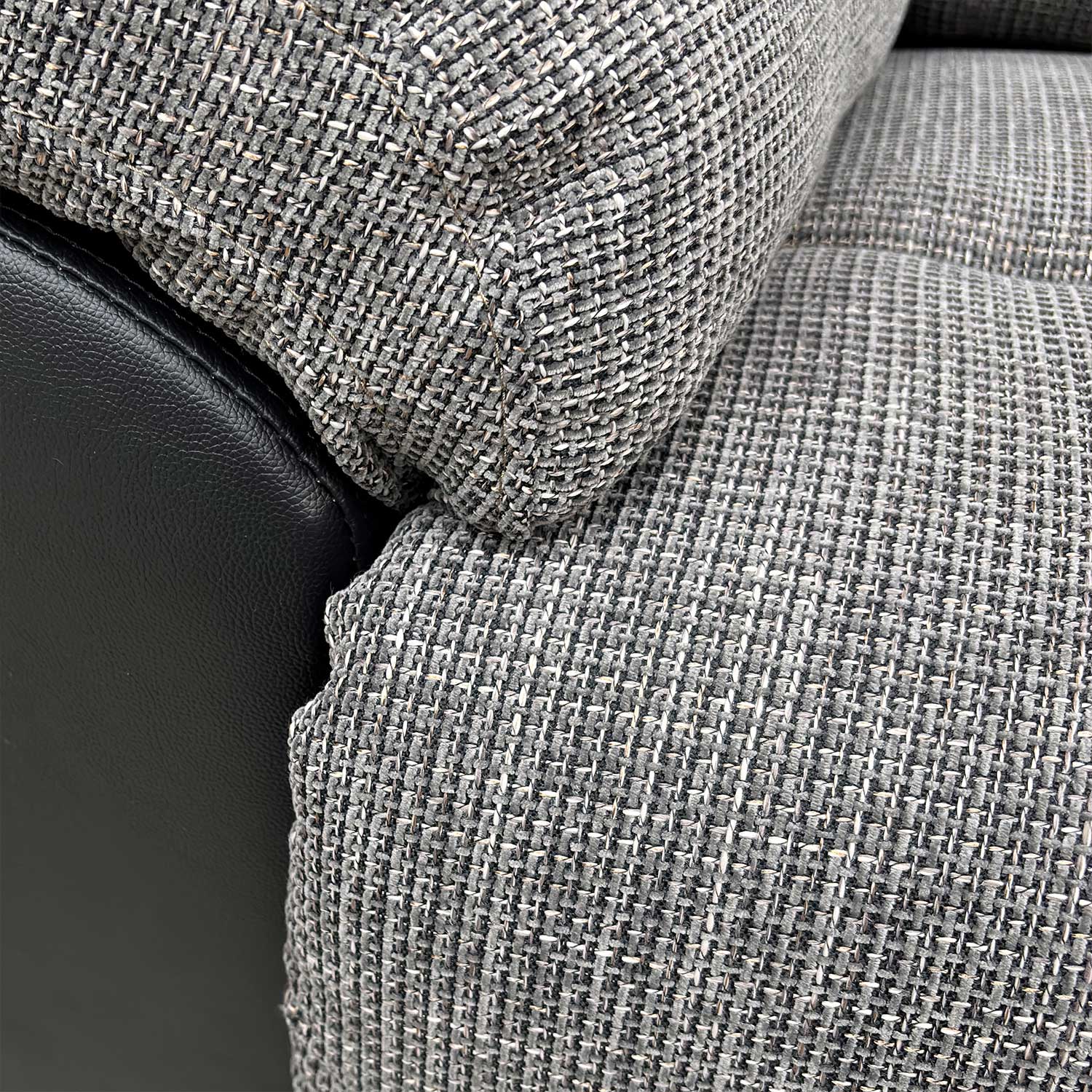 Close-up of the durable charcoal fabric upholstery and stitched detailing.
