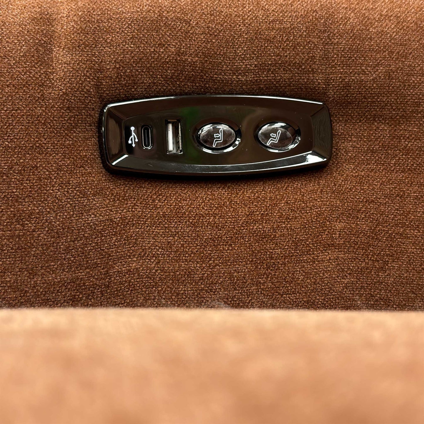 Close-up of the integrated metallic power reclining buttons located on the side of the sofa.
