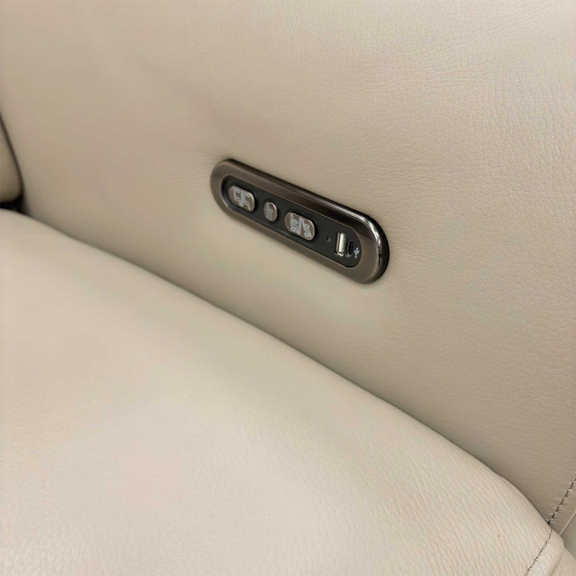 Close-up of the integrated power reclining and headrest control buttons located on the side of the sofa.