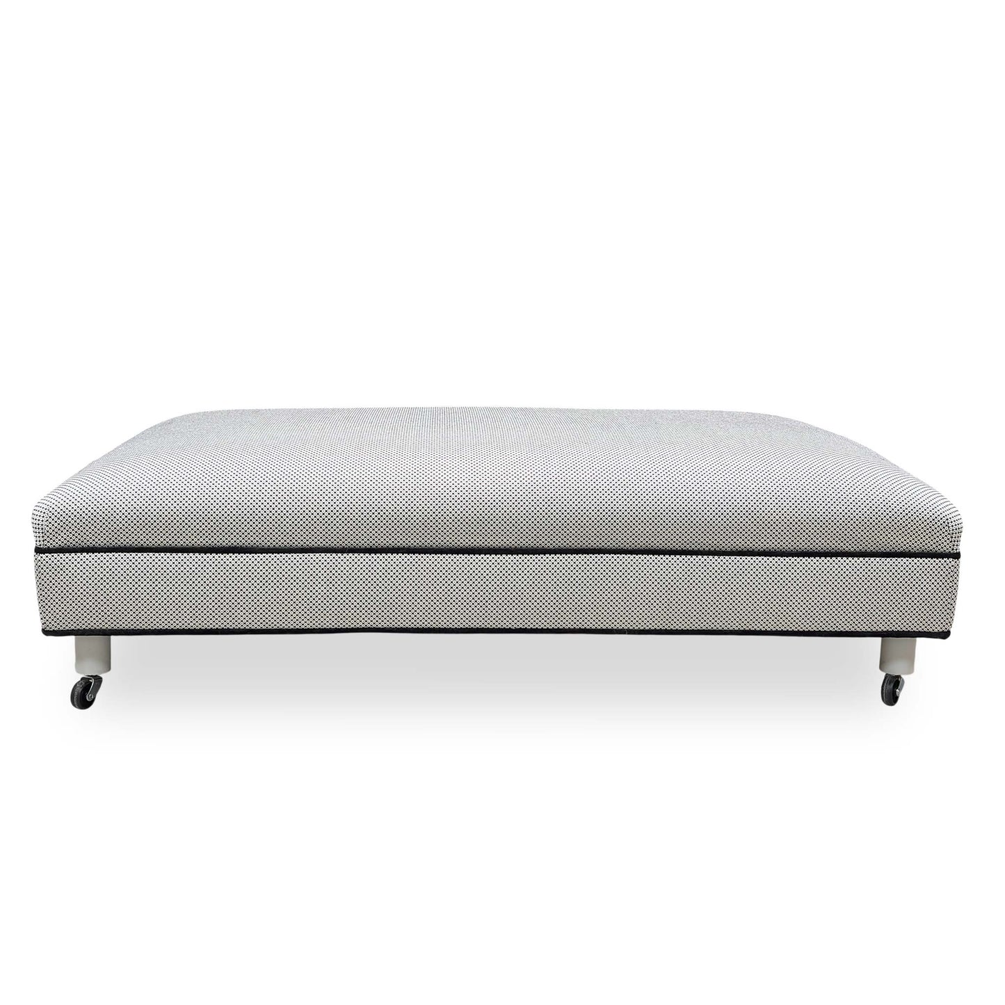 Side profile of the Ambassador footstool showing the uniform upholstered base and sleek contemporary silhouette.