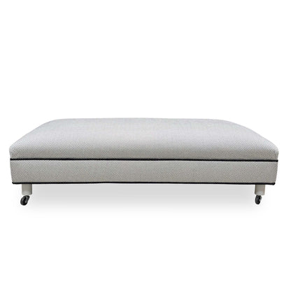 Side profile of the Ambassador footstool showing the uniform upholstered base and sleek contemporary silhouette.