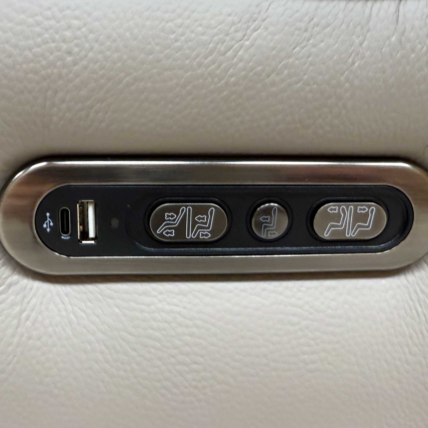Close-up of the integrated brushed metal power control buttons located on the outer side of the sofa.