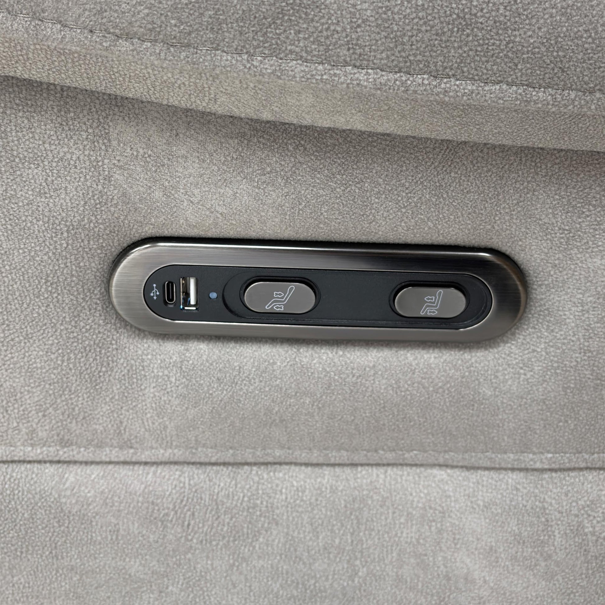 Close-up of the integrated chrome power reclining controls located on the side of the velvet armrest.