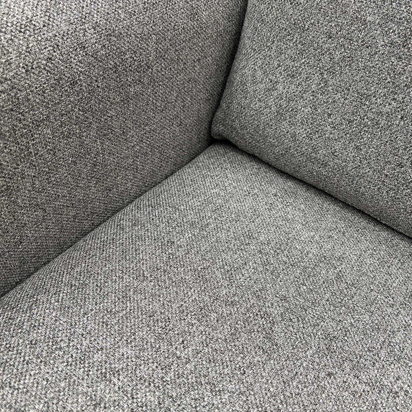 Detail shot of the premium silver grey fabric texture and high-quality stitching on the sofa armrest.