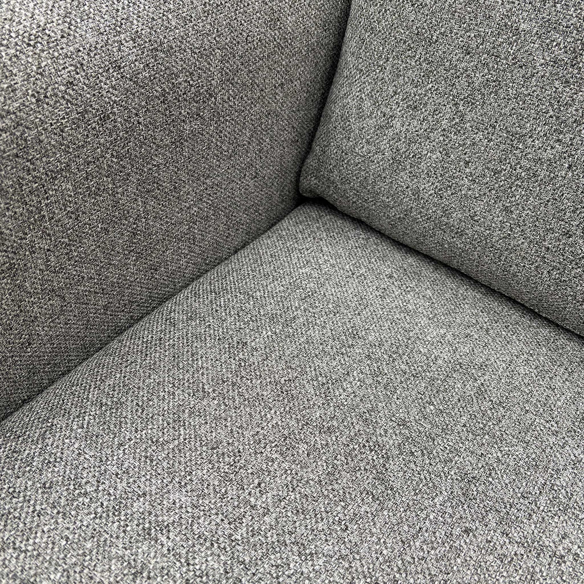Detail shot of the premium silver grey fabric texture and high-quality stitching on the sofa armrest.