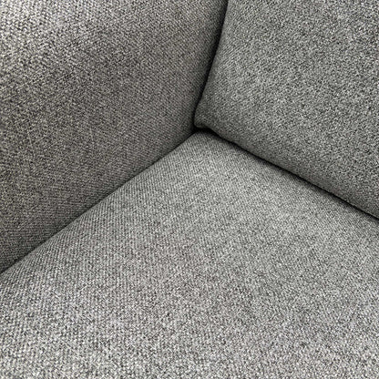 Detail shot of the premium silver grey fabric texture and high-quality stitching on the sofa armrest.