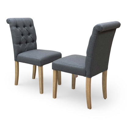 Full view of the ‘Lewis’ set of 2 anthracite fabric dining chairs with button-back detailing and dark wood legs.