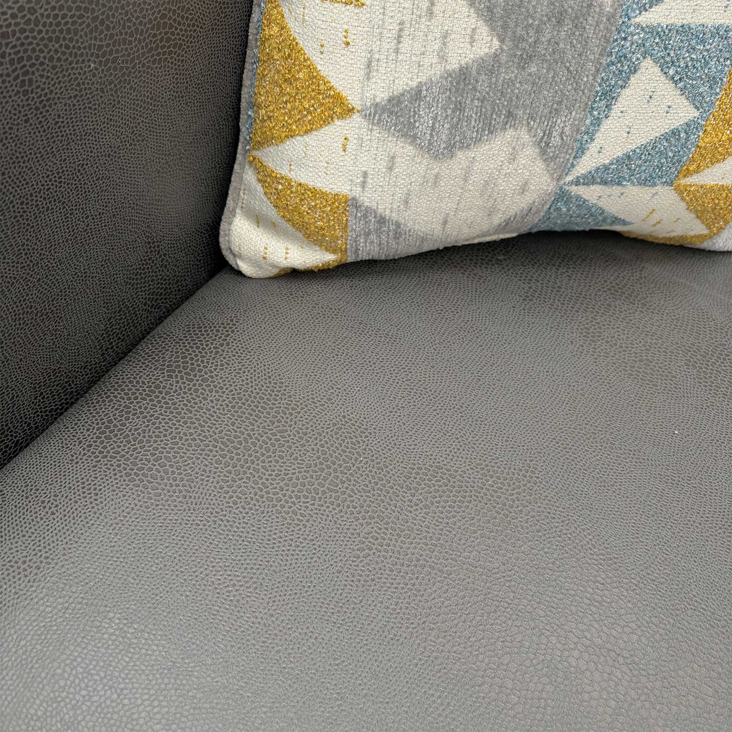 Close-up of the supportive seat cushions on the Newton sofa bed, upholstered in grey textured faux leather.