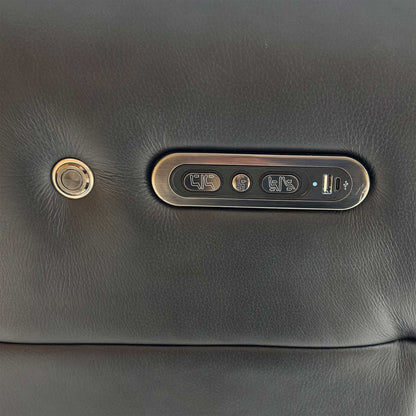 Close-up of the side-mounted power controls on the jet black leather sofa, featuring buttons for reclining, headrest adjustment, and a built-in USB charging port.