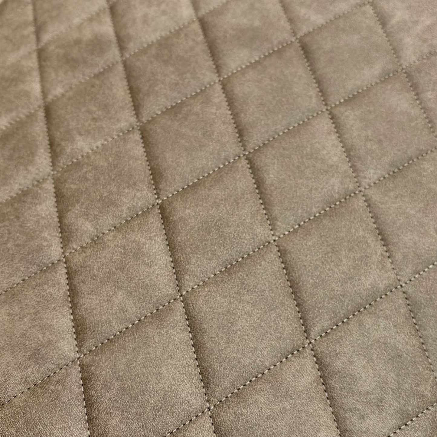 Close-up of the taupe fabric surface, showing the detailed quilted stitching and soft tactile finish.