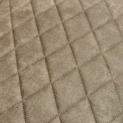 Close-up of the taupe fabric surface, showing the detailed quilted stitching and soft tactile finish.