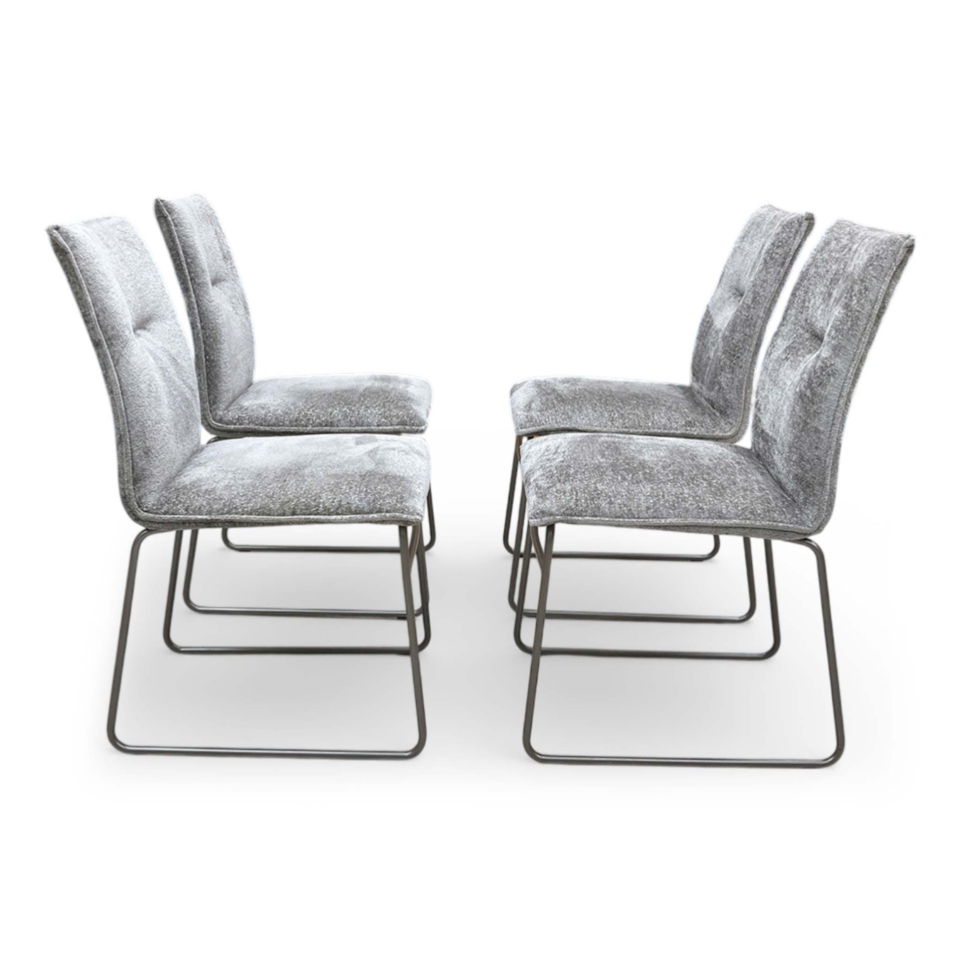 Front view of the chairs are elevated by striking ski-style legs made from tubular metal with a dark lava finish, offering a bold contrast to the neutral upholstery.