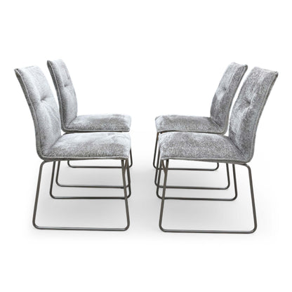 Front view of the chairs are elevated by striking ski-style legs made from tubular metal with a dark lava finish, offering a bold contrast to the neutral upholstery.