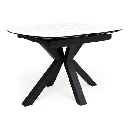 Side profile of the Raul table, showcasing the sleek black metal pedestal legs and the slim profile of the ceramic-on-glass top.