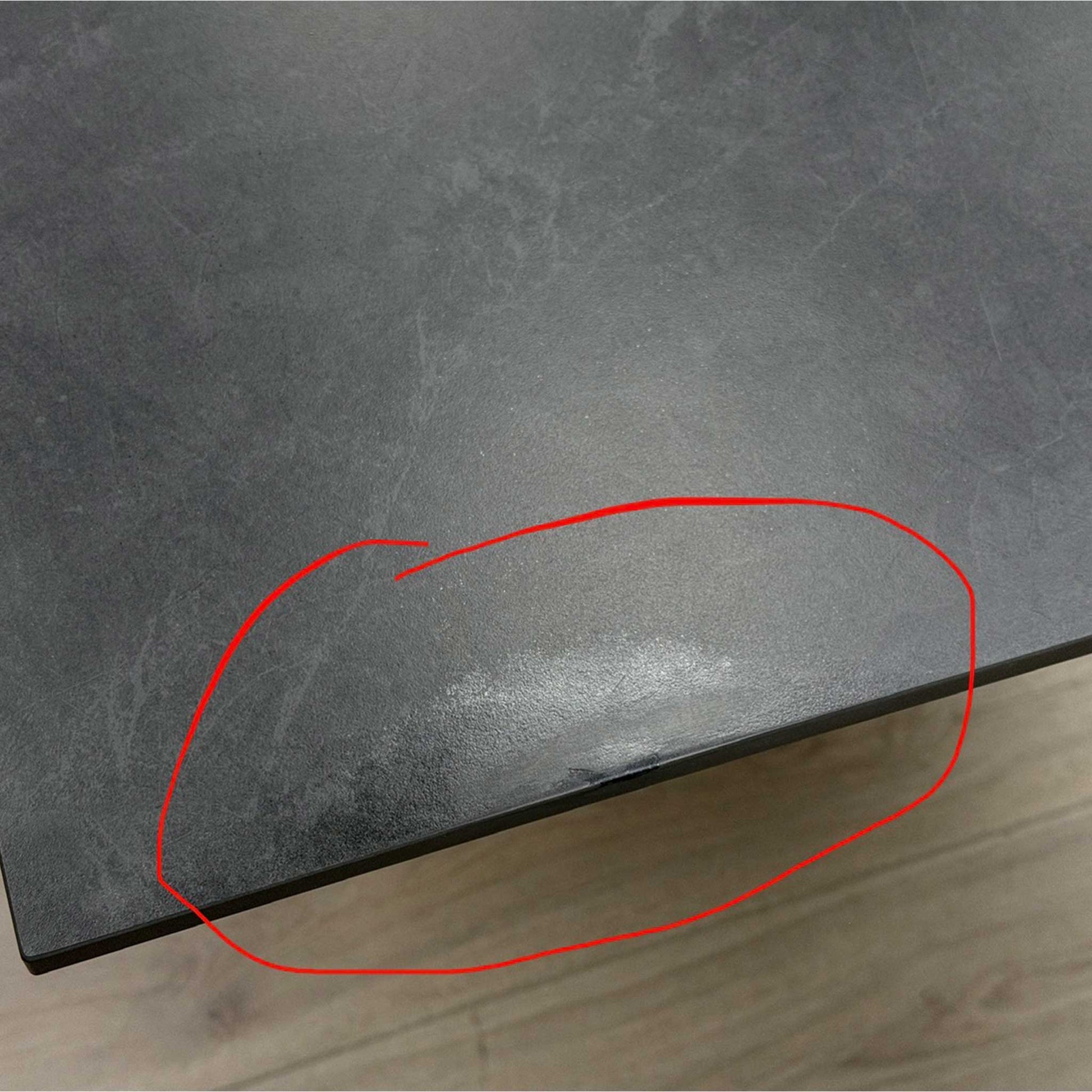 Close-up photo showing a specific area of small damage on the table top for transparency.