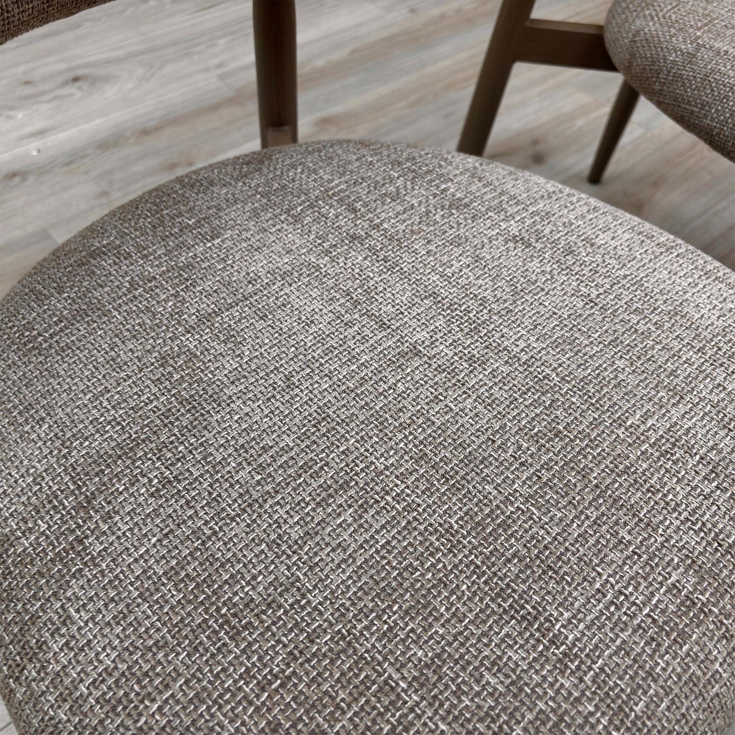 Close-up of an Aimar chair in a real-world setting, highlighting the tactile oatmeal upholstery and contemporary frame.
