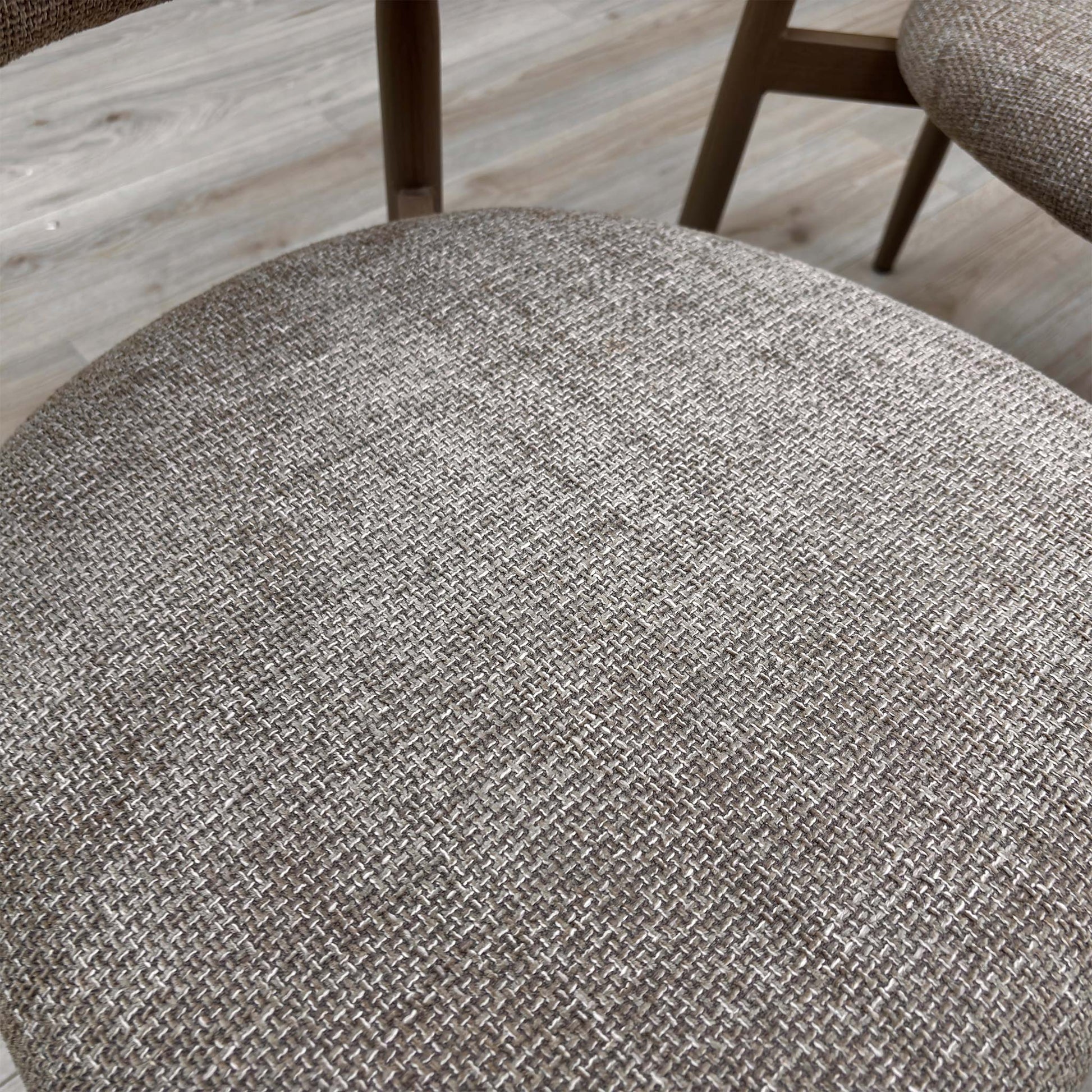 Close-up of an Aimar chair in a real-world setting, highlighting the tactile oatmeal upholstery and contemporary frame.