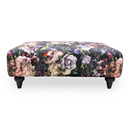 Frontal view the Dame floral footstool shown from a low angle, emphasizing its versatile use as a footrest or extra seating.