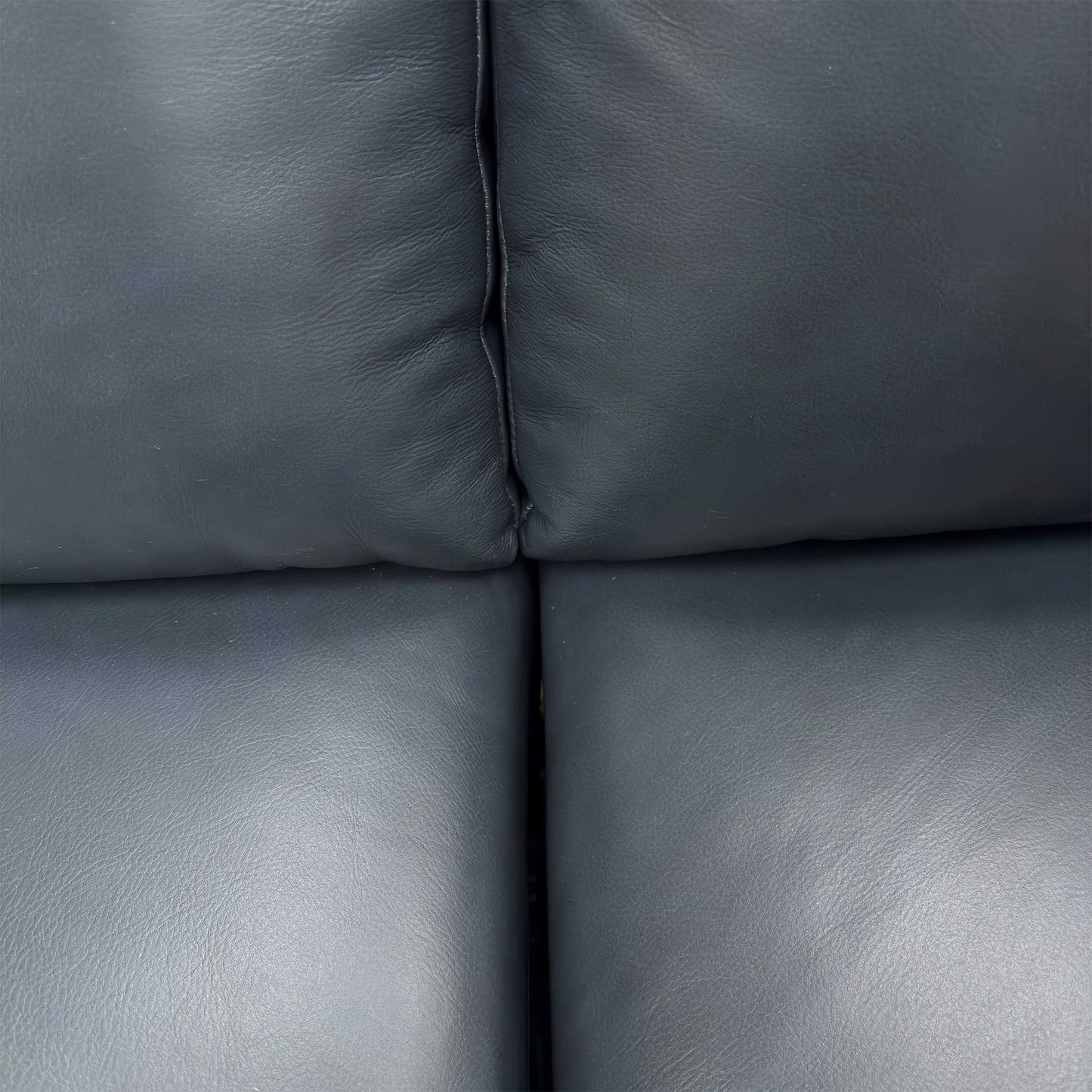 Close-up of the premium natural milled navy blue leather texture and padded armrests.