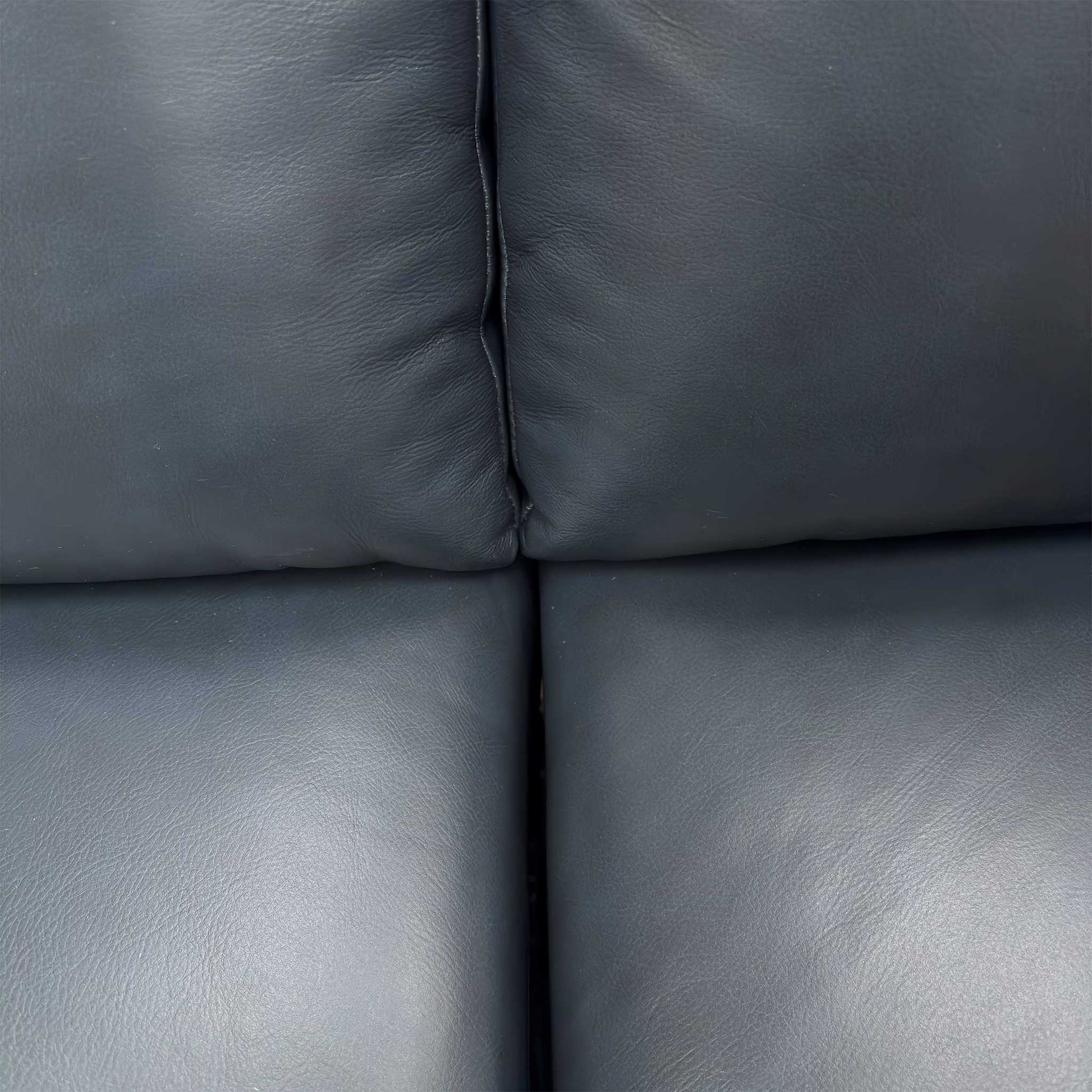 Close-up of the premium natural milled navy blue leather texture and padded armrests.