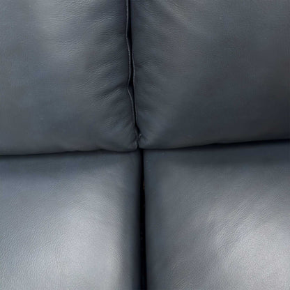 Close-up of the premium natural milled navy blue leather texture and padded armrests.