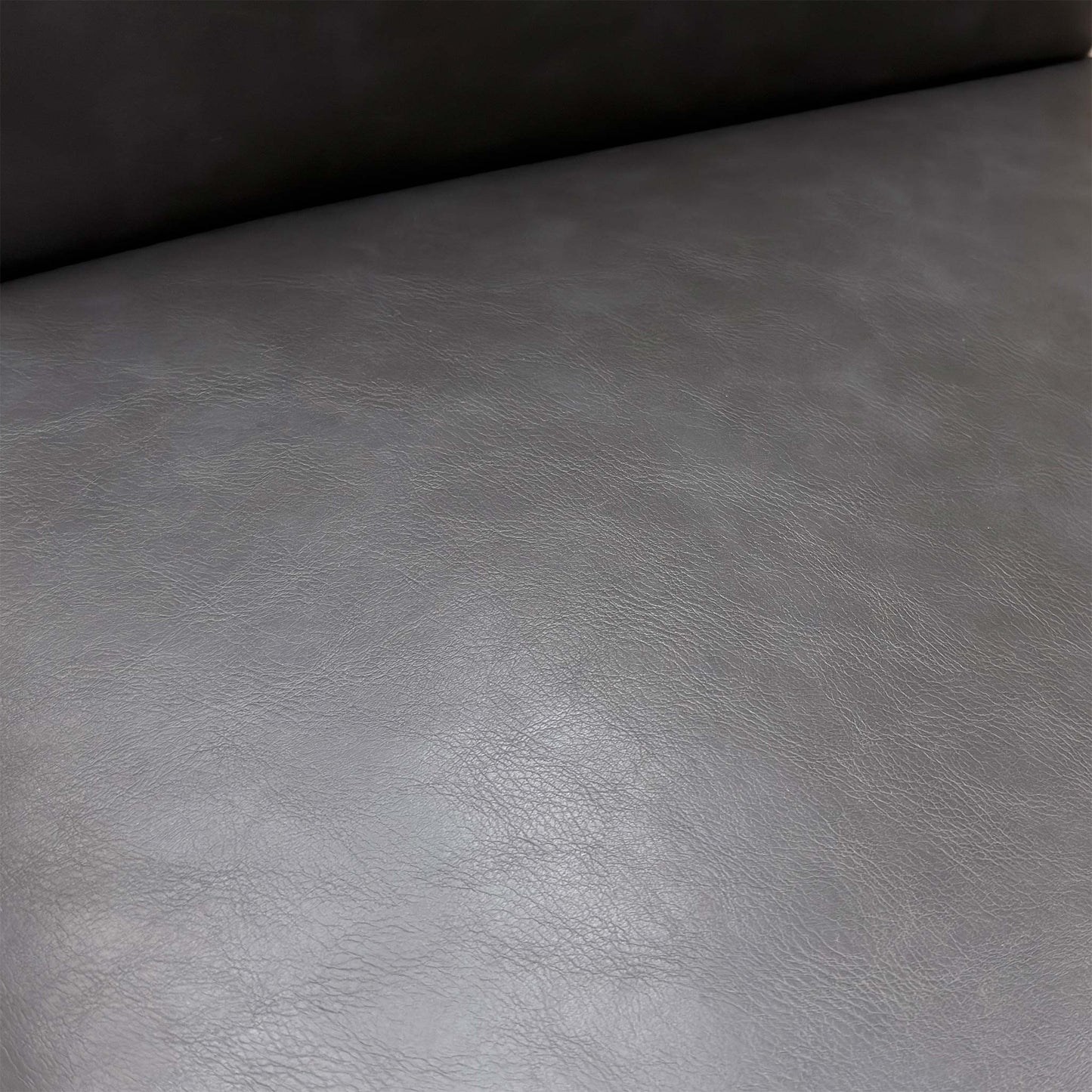 Close-up of the dark grey faux leather upholstery and elegant buttoned finish on the backrest.