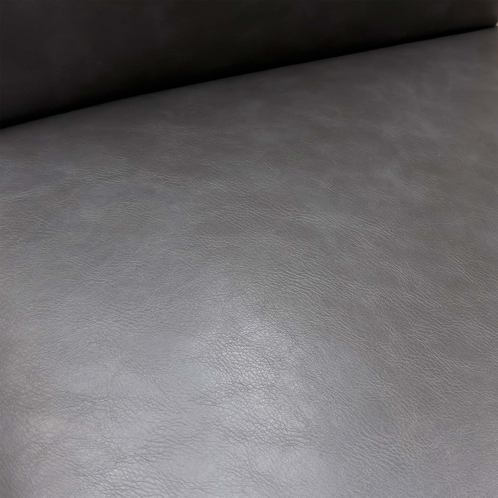 Close-up of the dark grey faux leather upholstery and elegant buttoned finish on the backrest.
