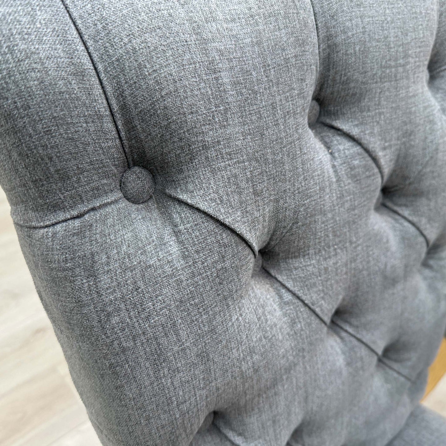 Close-up of a single Hamilton dining chair showing the detailed button-tufting on the charcoal grey fabric backrest.