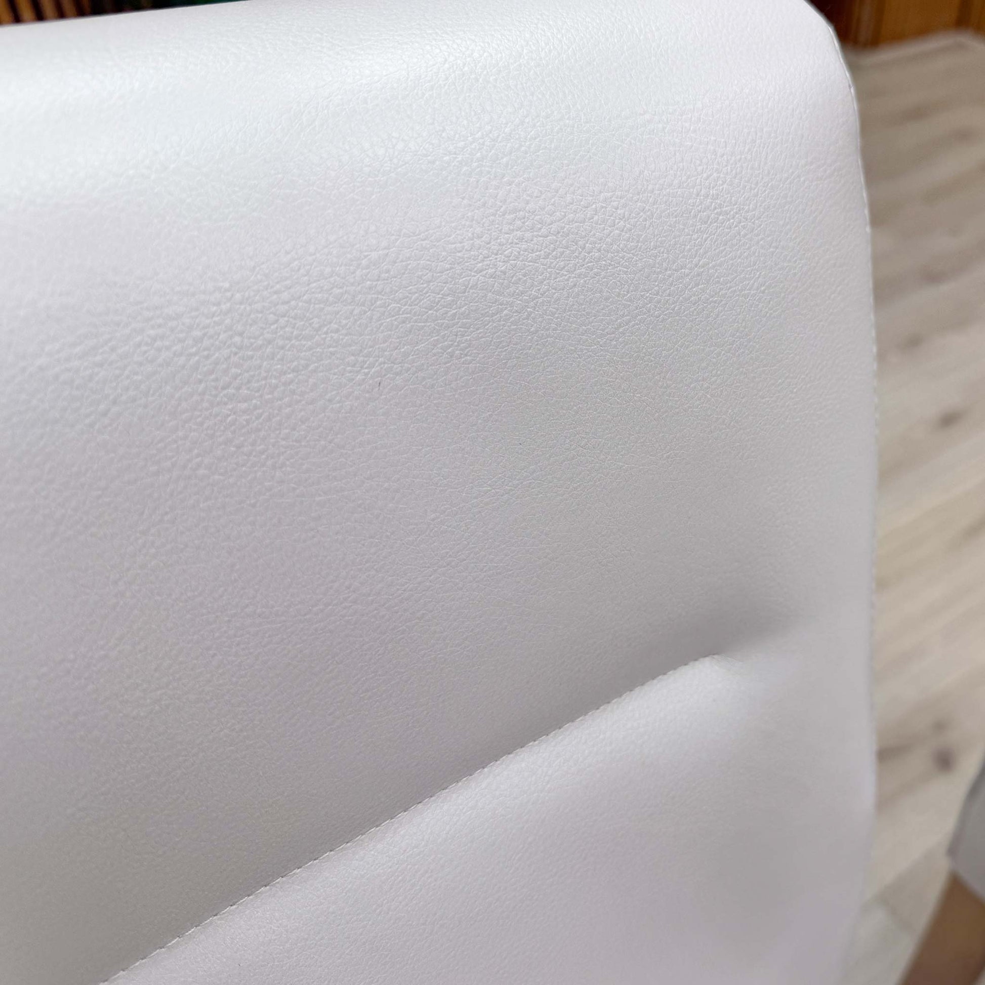 Close-up of the light grey faux leather and deep buttoned detailing on the backrest.