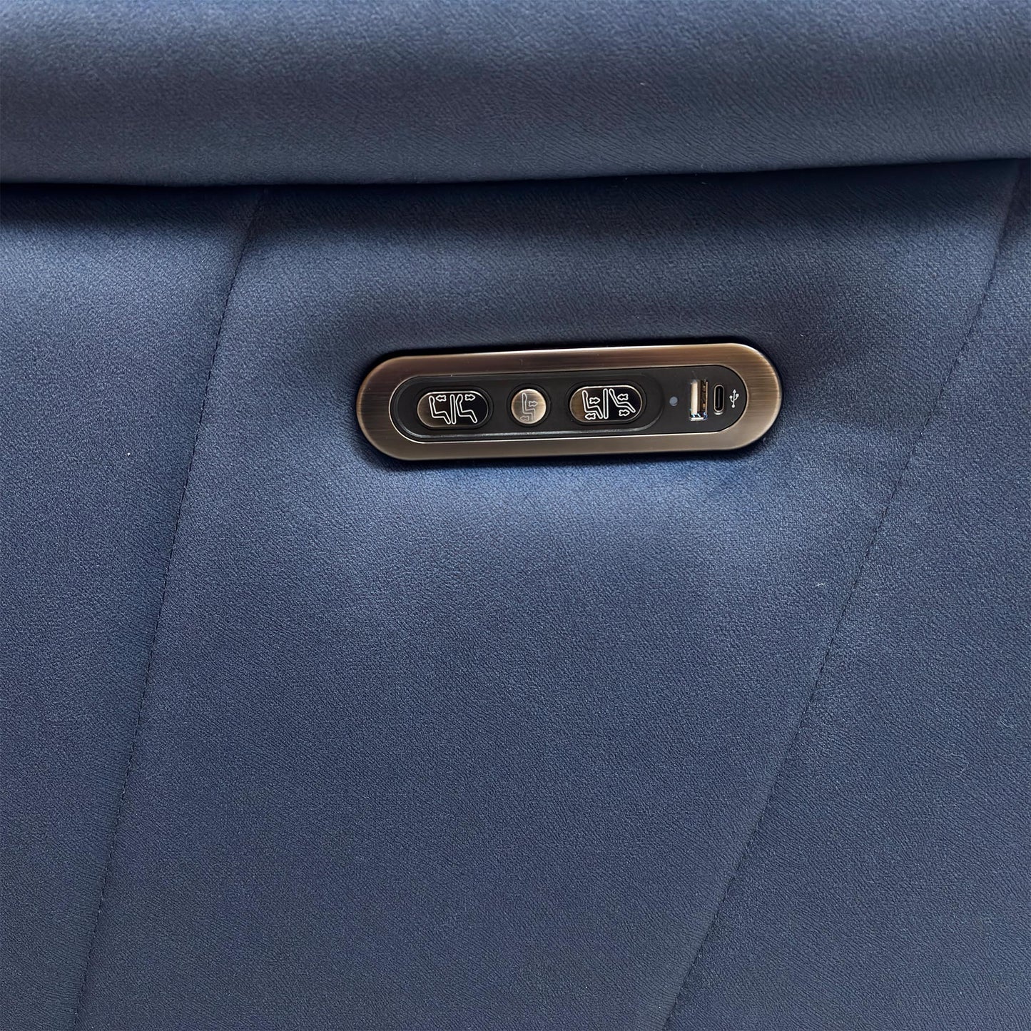 Detail shot of the metallic side control panel, showing the buttons for the power recliner, headrest, and the integrated USB charging port.