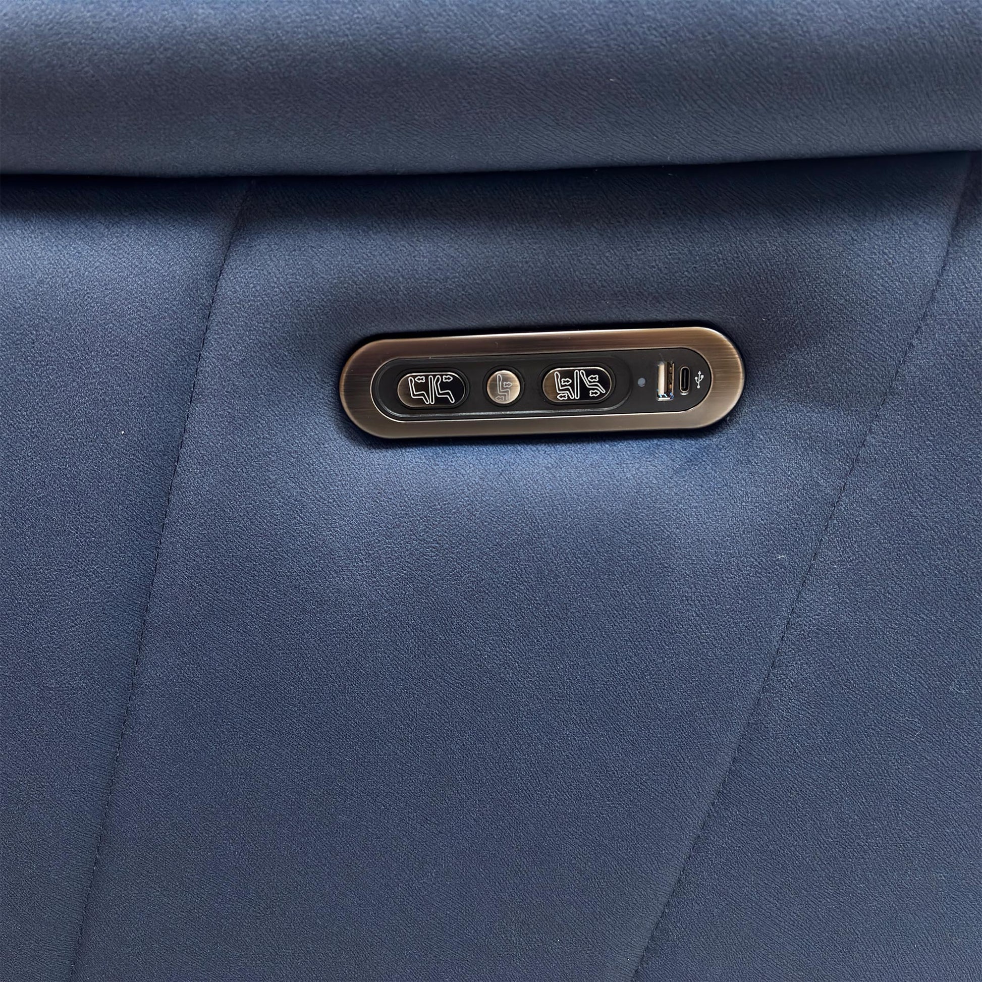 Detail shot of the metallic side control panel, showing the buttons for the power recliner, headrest, and the integrated USB charging port.