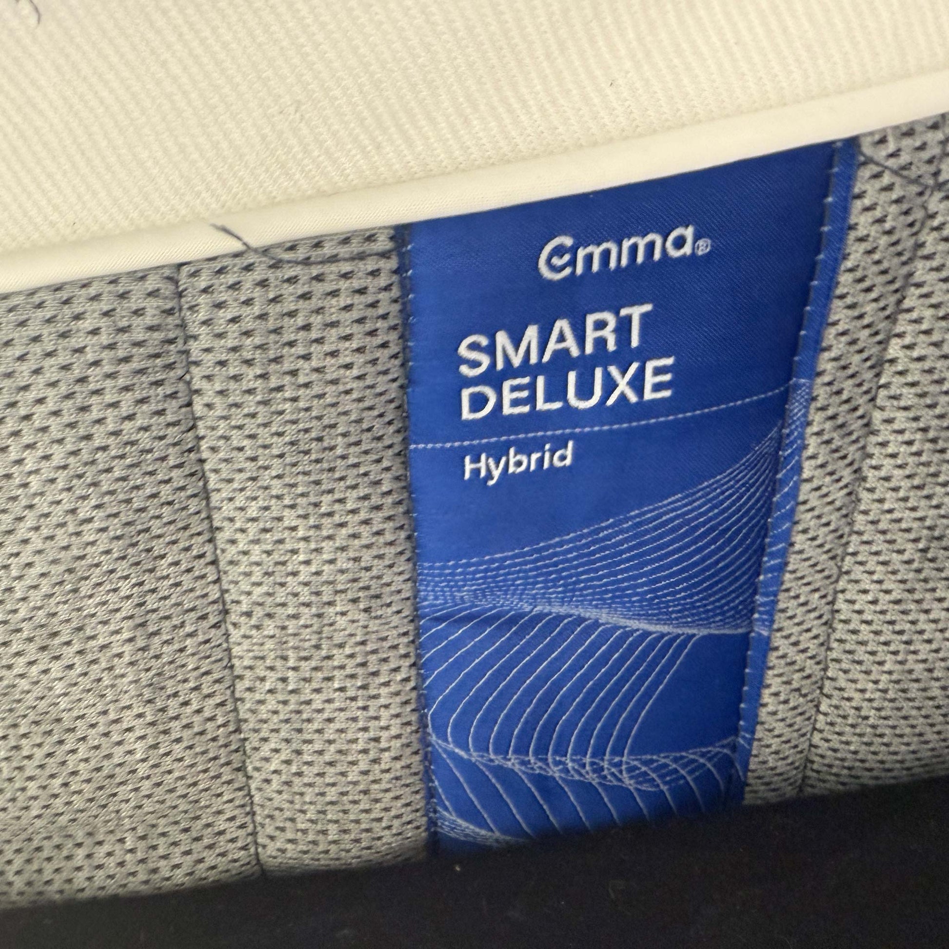 Close-up of the Emma branding logo embroidered on the side of the mattress border.