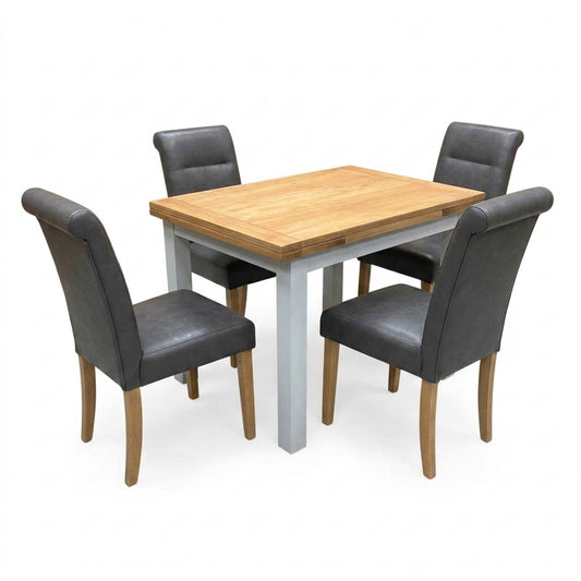 Lewis solid oak extending dining table, closed, with four dark grey faux leather roll back chairs, angled view