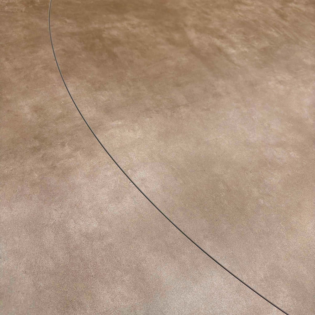 Close-up of the argile grey ceramic top on the Raul dining table showing the curved join line of the extension