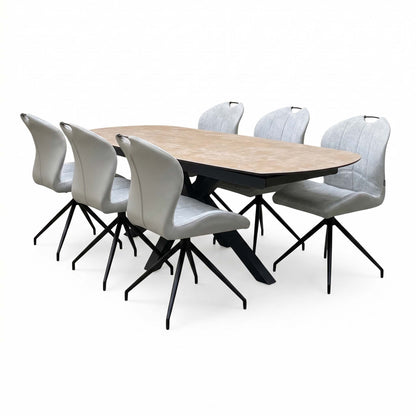 Raul extending dining table at full length with six stone grey swivel chairs, angled from the right