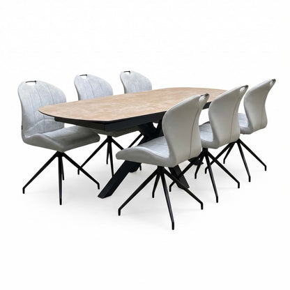 Angled view from the left of the extended Raul ceramic dining table with three stone grey swivel chairs each side