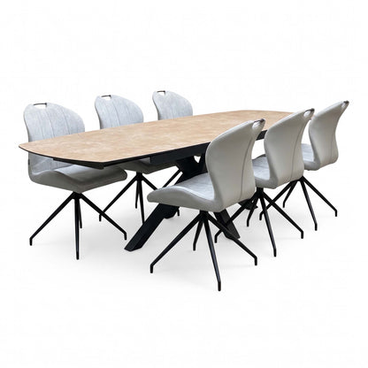 Raul argile grey ceramic extending dining table fully extended with six stone grey fabric swivel chairs, angled view