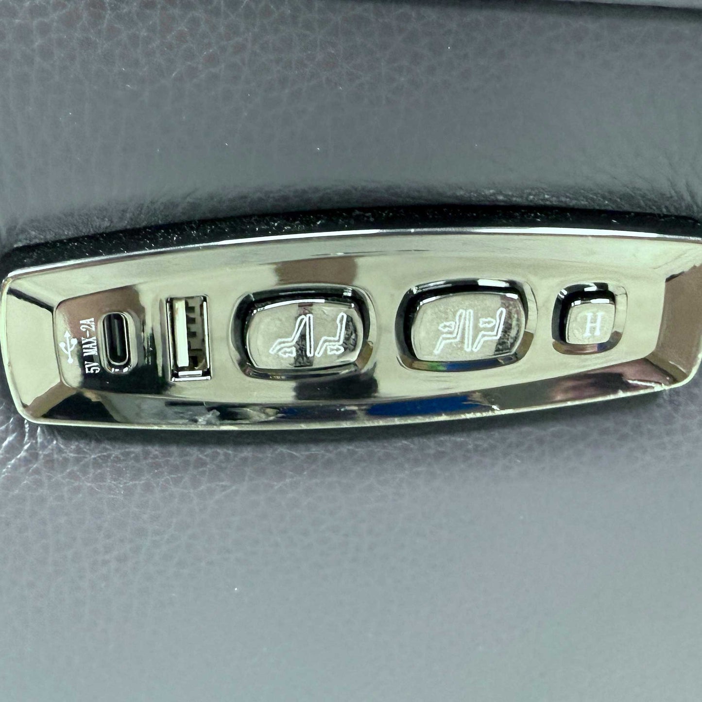 Detailed shot of the integrated power reclining controls and USB charging port located on the outer side of the armrest.