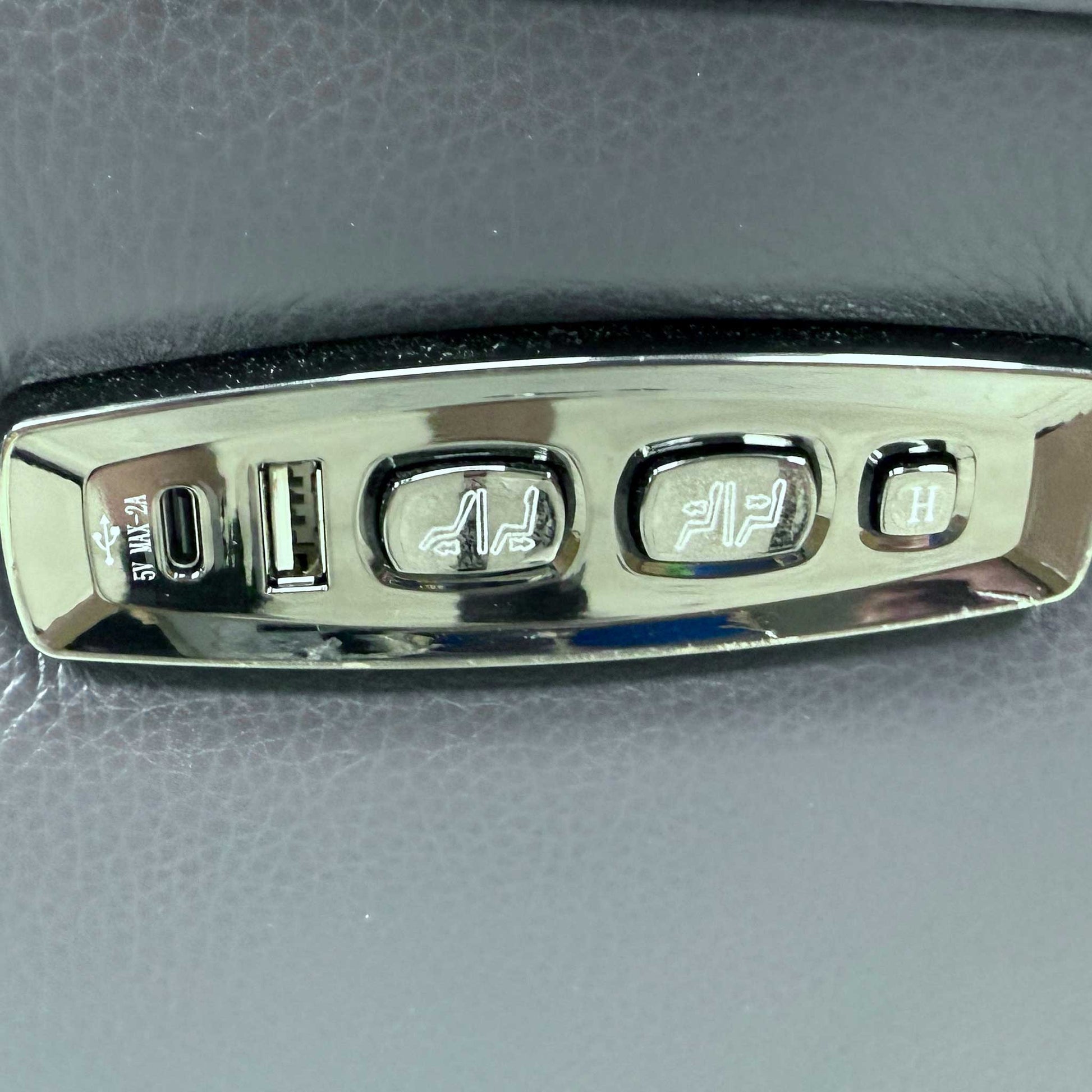 Detailed shot of the integrated power reclining controls and USB charging port located on the outer side of the armrest.