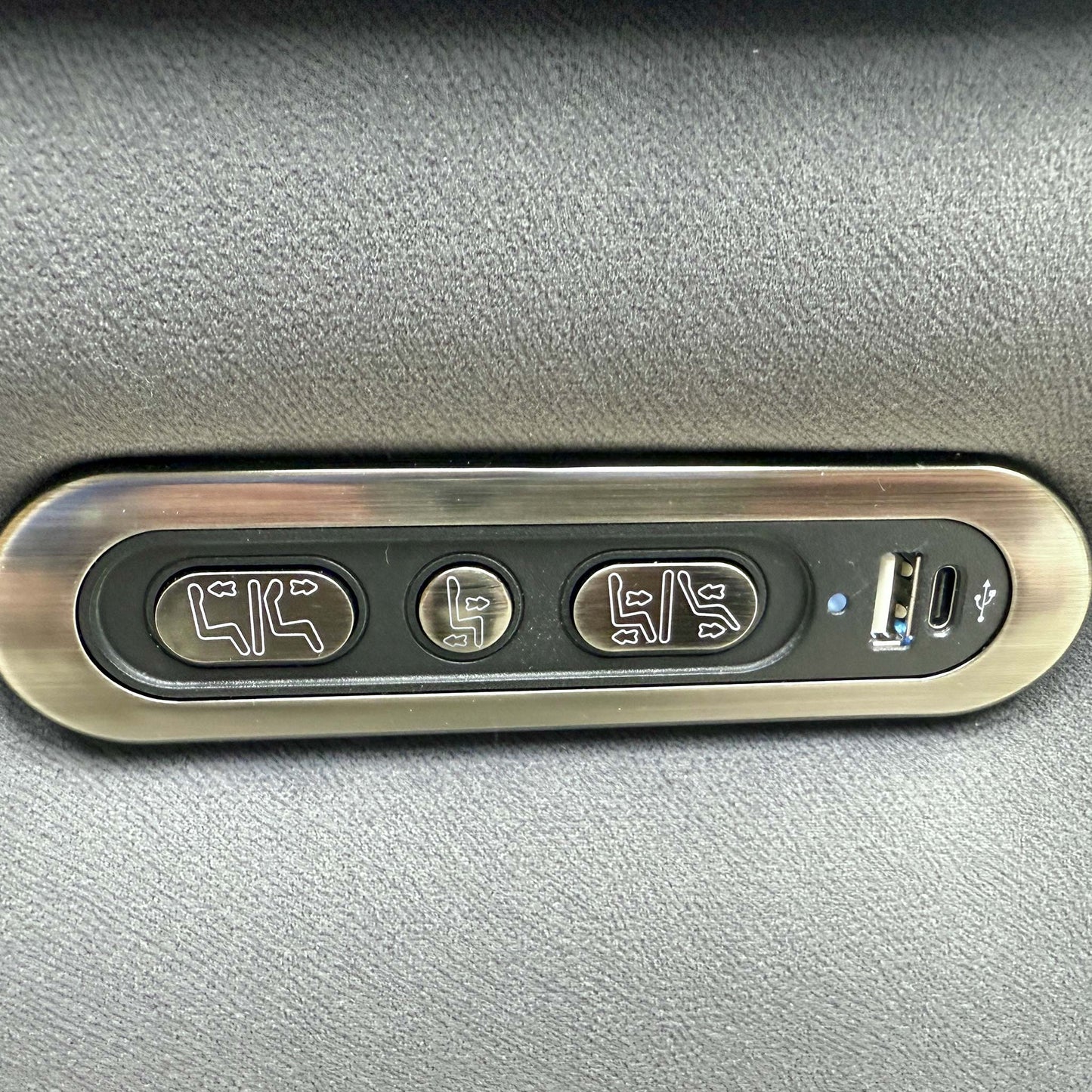 Detailed shot of the integrated power controls on the side of the armrest, featuring buttons for reclining, headrest adjustment, and a USB port.