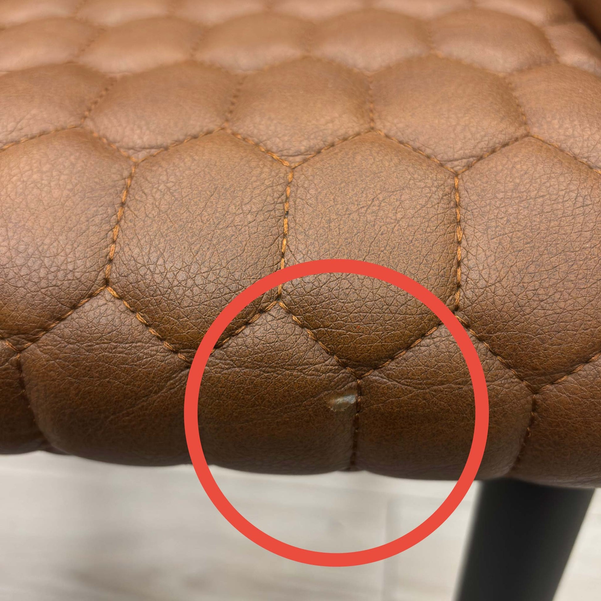 Side view of the chair frame, highlighting a minor scratch or paint chip on the lower section of the black metal leg.