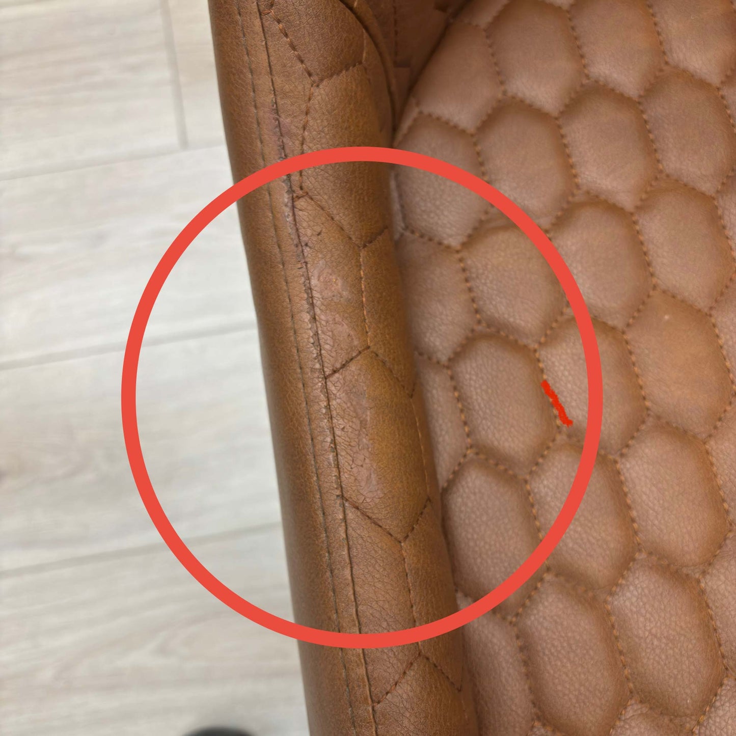 Close-up of the seat cushion edge, showing a slight compression or minor crease in the faux leather material.