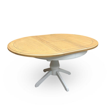 Full view of the Furnitureland 'Hamilton' round extending dining table in solid oak, showing its clean, classic silhouette and natural wood grain.