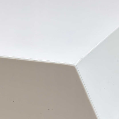 Close-up of the glossy white surface, highlighting the smooth, mirror-like finish and the precision-engineered joints between the leaves.