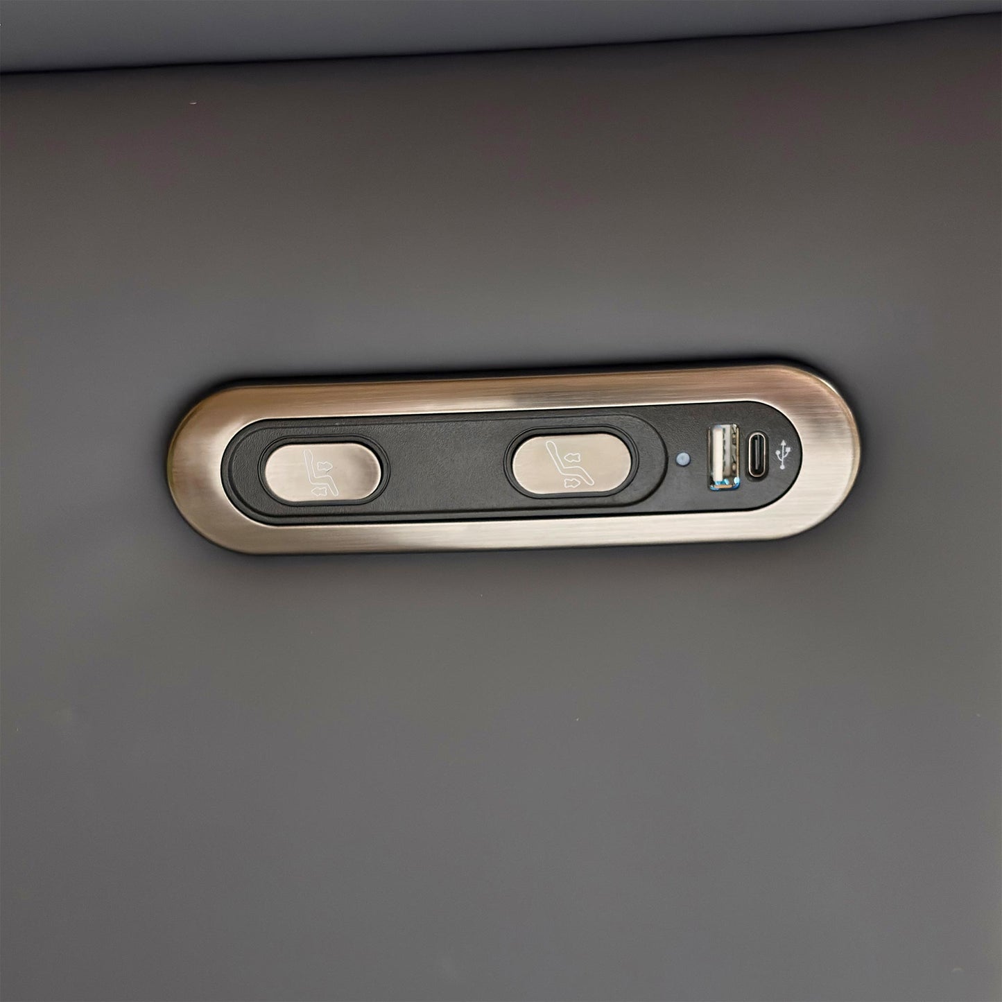 Detail shot of the power control buttons on the side of the armrest, showing the integrated USB charging port.