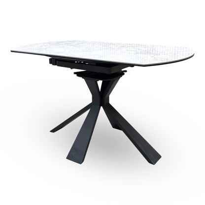 Side view of the Crete dining table in its compact round form, showcasing the durable textured stone finish and the architectural geometric leg design.